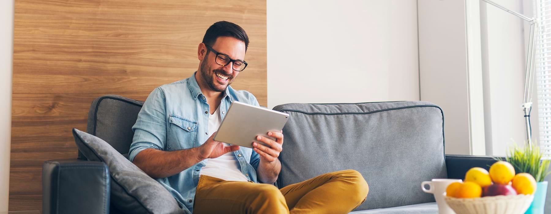 Young Man Sitting On Couch Using An Electronic Tablet