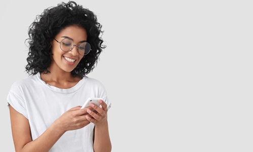 smiling woman with glasses texts on her cell